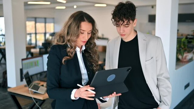 Business session in an office. Woman and a young man discussing business affairs, tablet. Slow motion