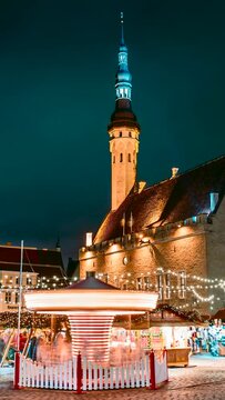 Tallinn, Estonia. vertical footage Time-lapse Of Traditional Christmas Market And Carousel In Town Hall Square. Famous Landmark And UNESCO World Heritage Site. Christmas Tree And Trading Houses.