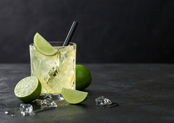 Gimlet Kamikaze cocktail in crystal glass with lime slice and ice on black board.