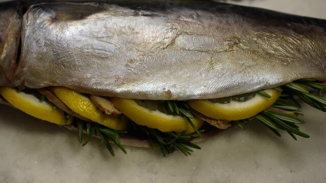 Fresh fish stuffed with lemon, rosemary, ginger, on a large amount of salt before baking. The process of cooking fish in a salt shell flamb&eacute; in the oven. Close up, panorama