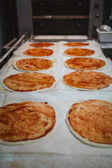 Many uncooked pizza base ready to be baked in the oven of artisan bakery
