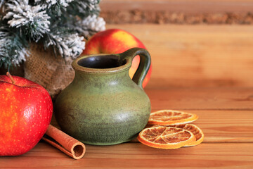 A ceramic jug for mulled vine on wooden table. Christmas decorations around.