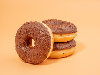 Chocolate donut with chocolate chips on an orange background. close-up.
