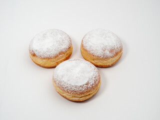 Freshly baked and dusted with powdered sugar German donuts. Donut berliner or krapfen on white background.