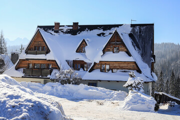 BUKOWINA TATRZANSKA, POLAND - FEBRUARY 09, 2023: Wooden home under the snow in Bukowina Tatrzanska, Poland.