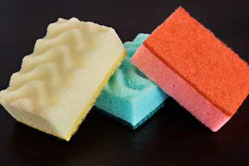 Multicolored kitchen sponges for washing dishes on a dark background.