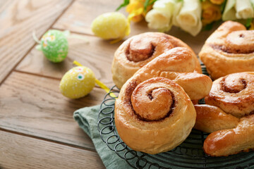 Easter breakfast Holliday concept. Easter bunny buns rolls with cinnamon made from yeast dough with orange glaze, easter decorations, colored eggs on old wooden background. Easter Holliday card.