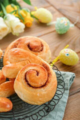 Easter breakfast Holliday concept. Easter bunny buns rolls with cinnamon made from yeast dough with orange glaze, easter decorations, colored eggs on old wooden background. Easter Holliday card.