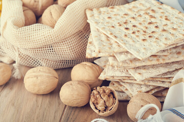 Passover celebration concept. Matzah, red kosher and walnut. Traditional ritual Jewish bread matzah, kippah and tallit on old wooden background. Passover food. Pesach Jewish holiday. Toned image.