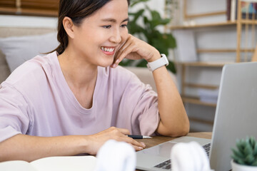 Happy asian woman  in online learning , enjoying watching educational webinar on laptop. Smiling...