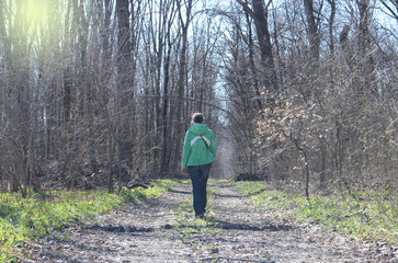 A young woman is walking along a forest road. Spring forest.