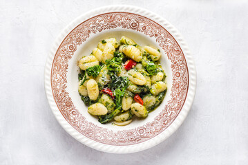 Gnocchi with  turnip leaves and tops or cima di rapa with chili pepper, olive oil and  Parmesan cheese.  Mix  recipes of south, Puglia, and nord of Italy.  White table, top view,  vintage dish