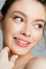 Obraz premium Portrait of smiling woman with perfect skin looking away isolated on grey.