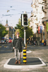Outdoor portrait of handsome young man posing in the middle of the road next to traffic light