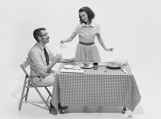 Monochrome portrait of family couple sitting at the table, having breakfast. Woman caring after man. Concept of love, relationship, retro style
