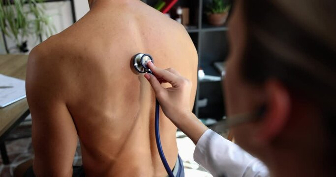 The doctor presses the stethoscope to the patient back