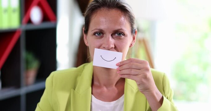 A businesswoman in an office with a fake smile on paper
