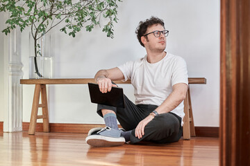 Portrait of a young white man sitting on floor looking around 