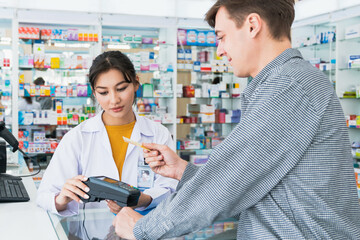 Payment by credit card with payment terminal in qualified drugstore. Modern financial payment of electric money. Caucasian customer purchase medication in pharmacy with prescription from pharmacist. - obrazy, fototapety, plakaty