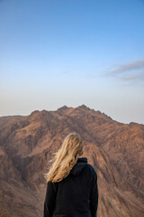 Blond girl on top of mountain.