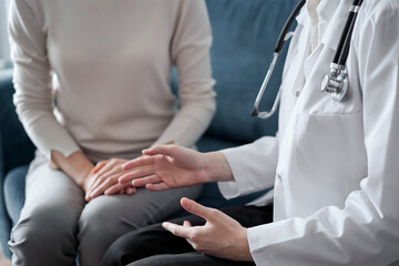 Obraz premium Doctor and patient discussing current health examination while sitting at sofa in clinic office, closeup. Medicine concept
