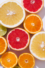 Fresh citrus fruit: oranges, red blood oranges(tarocco), pomelo, lime om the white background , sunlight, top view, close up