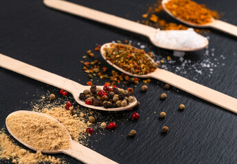 spices on wooden spoons on black board
