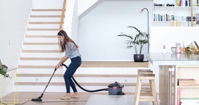 Vacuum, cleaning and dance with a woman cleaner having fun in her home while singing during chores. Music, living room and housekeeping with a female in her house to clean for domestic hygiene