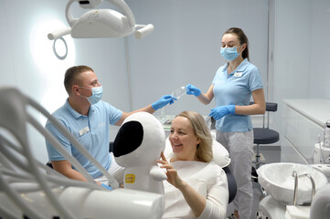 dental clinic middle aged woman sitting in chair with astronaut soft toy smiling pretty showing...