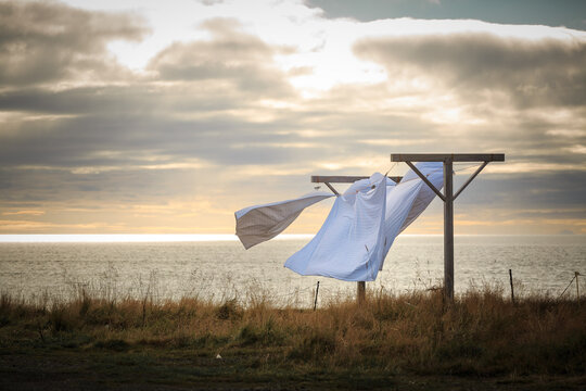 weiße Wäsche trocknet im Wind und Wetter draußen Hier am Meer , die Sonne schaut noch ein bisschen durch die Wolken.