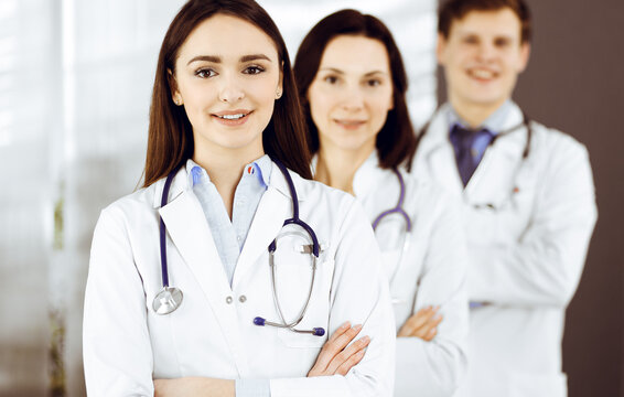 Group of young professional doctors is standing as a team with arms crossed in a hospital office and is ready to help patients. Medical help, insurance in health care, and medicine concept
