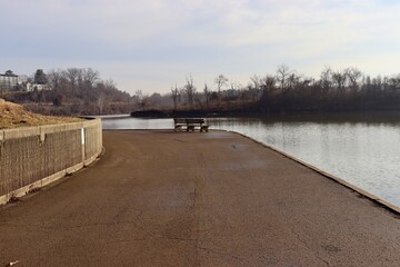 Naklejka premium The empty park bench near the lake in the park.