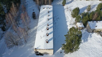 Ruins of an old farm. The buildings of the former Soviet collective farm in the middle of the forest under the snow in the cold. Abandoned buildings of the agricultural state farm of the USSR.