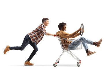 Fototapeta na wymiar Young caucasian man pushing an african american guy inside a shopping cart