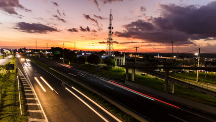 Fototapeta na wymiar Marilia, Sao Paulo, Brazil, January 26, 2023. traffic on the Highway and silhouette of a telecommunications antenna in Marilia city, during a sunset
