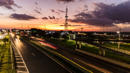 Fototapeta na wymiar Marilia, Sao Paulo, Brazil, January 26, 2023. traffic on the Highway and silhouette of a telecommunications antenna in Marilia city, during a sunset