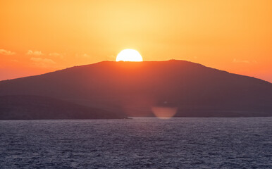 Naklejka na ściany i meble Rocky Island on Mediterranean Sea. Rinia near Mikonos, Greece, Europe. Nature Background. Sunrise Sky