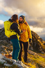 couple in love looking into each other's eyes on the top of a mountain. couple of hikers climbing a mountain peak at sunset. outdoor adventure sport