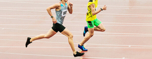 two athlete runners run track stadium in rainy weather