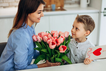 Fototapeta na wymiar I love my mom! Cute son congratulate his mother with Mother`s day. Spending time together at home. Happy family concept
