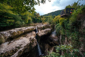 Obraz premium Beautiful natural canyon with view of the mountain river, and rocks, christal blue water, green tree, Summer day time. Travel and active life style. Vacation. Martvili in Georgia near Kutaisiv