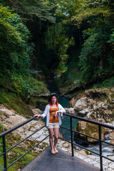 Naklejka na ściany i meble Girl, woman tourist. Admire the beautiful view of nature in the Martvili canyon. Mountain area, Abasha river. Concept of Tours to Georgia. Front view. Vertical photo.