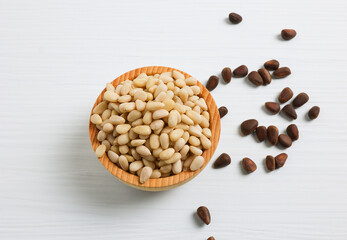 pine nuts in a wooden bowl on a wooden background. Soft focus.