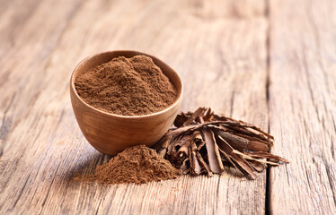 Cinnamon bark with powder on wooden background