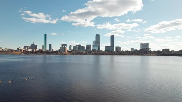 Drone and aerial establishing moving shot towards high-rise skyscrapers, tall apartments, and business developments in downtown Boston, Massachusetts on a sunny, winter day near the Charles River