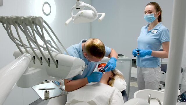dental treatment in dental clinic using liquid rubber dam to protect against photopolymer lamp glasses nurse and doctor work with patient people honesty sterility patient care optragate mouth expander