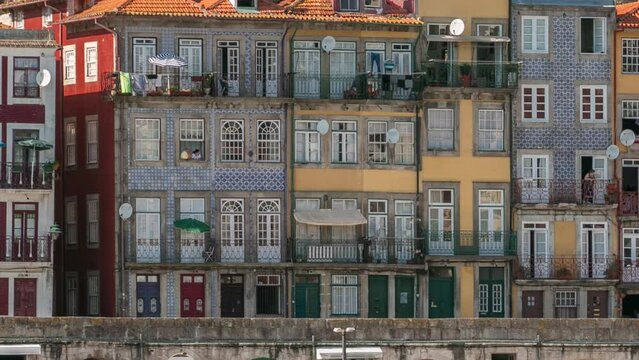 Waterfront with traditional quaint houses in the old, vintage and touristic ribeira district of Porto at sunny day timelapse, Portugal. Aerial facade view