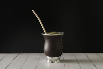 Chimarrão is a traditional drink from south of Brazil, Uruguai, Paraguai and Argentin. Isolated mate tea in a black and wooden background 