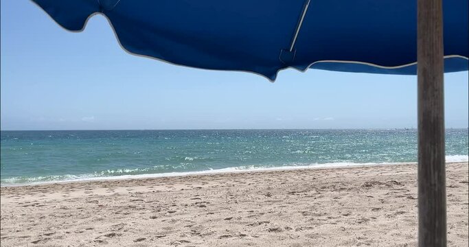Beach umbrella flaps in wind on south florida beachfront
