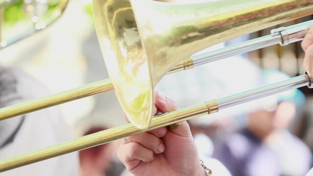 close up of a mexican hispanic musician with brown skin playing the trombone, wearing a watch and a gold bracelet